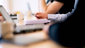 Blurred picture of a desk with computer and people working